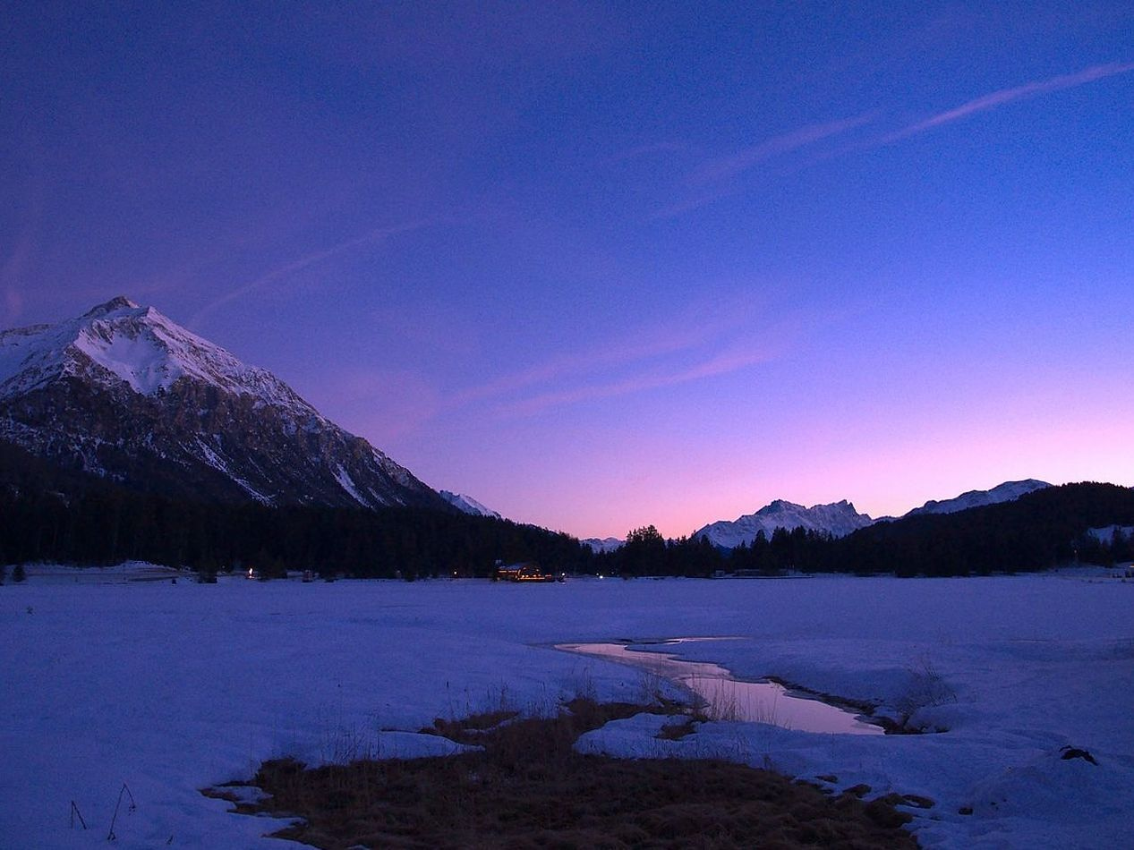 Orilla helada de un lago de montaña al amanecer